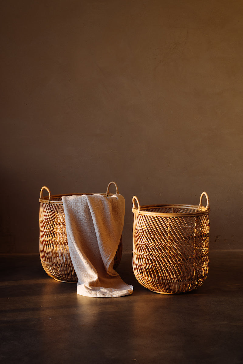 Op de afbeelding zijn twee mooie rotan manden te zien, handgemaakt van duurzaam materiaal. De manden hebben een organisch ontwerp en zijn perfect voor het opbergen van allerlei spullen, van speelgoed tot kleding. De warme kleur van het rotan voegt een natuurlijk en rustgevend element toe aan elke ruimte.