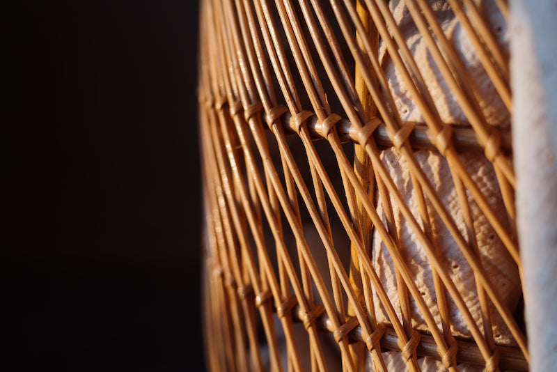 Op de afbeelding is een close-up te zien van een prachtige rotan mand, handgemaakt van duurzaam materiaal. Deze close-up foto toont de natuurlijke textuur en warme kleur van het rotan, waardoor deze mand een unieke en organische uitstraling heeft. De mand is perfect voor het opbergen van verschillende spullen en voegt een warm en gezellig element toe aan elke ruimte. Deze rotan mand is een stijlvolle en praktische toevoeging aan elke kamer.