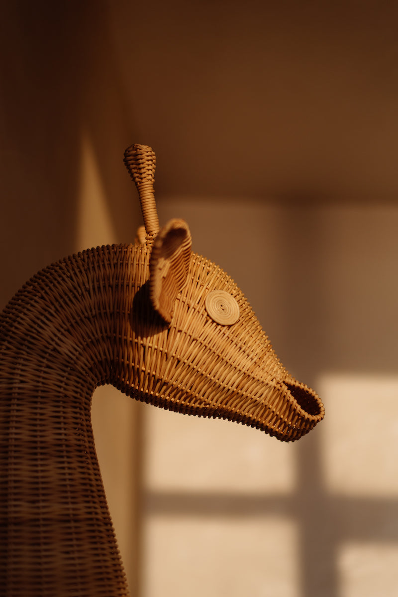 Op de afbeelding staat een charmante rotan giraffekop wanddecoratie, die een betoverende en exotische uitstraling biedt aan de kinderkamer. Handgemaakt van duurzaam materiaal, is deze decoratie een stijlvolle en duurzame toevoeging aan het interieur.