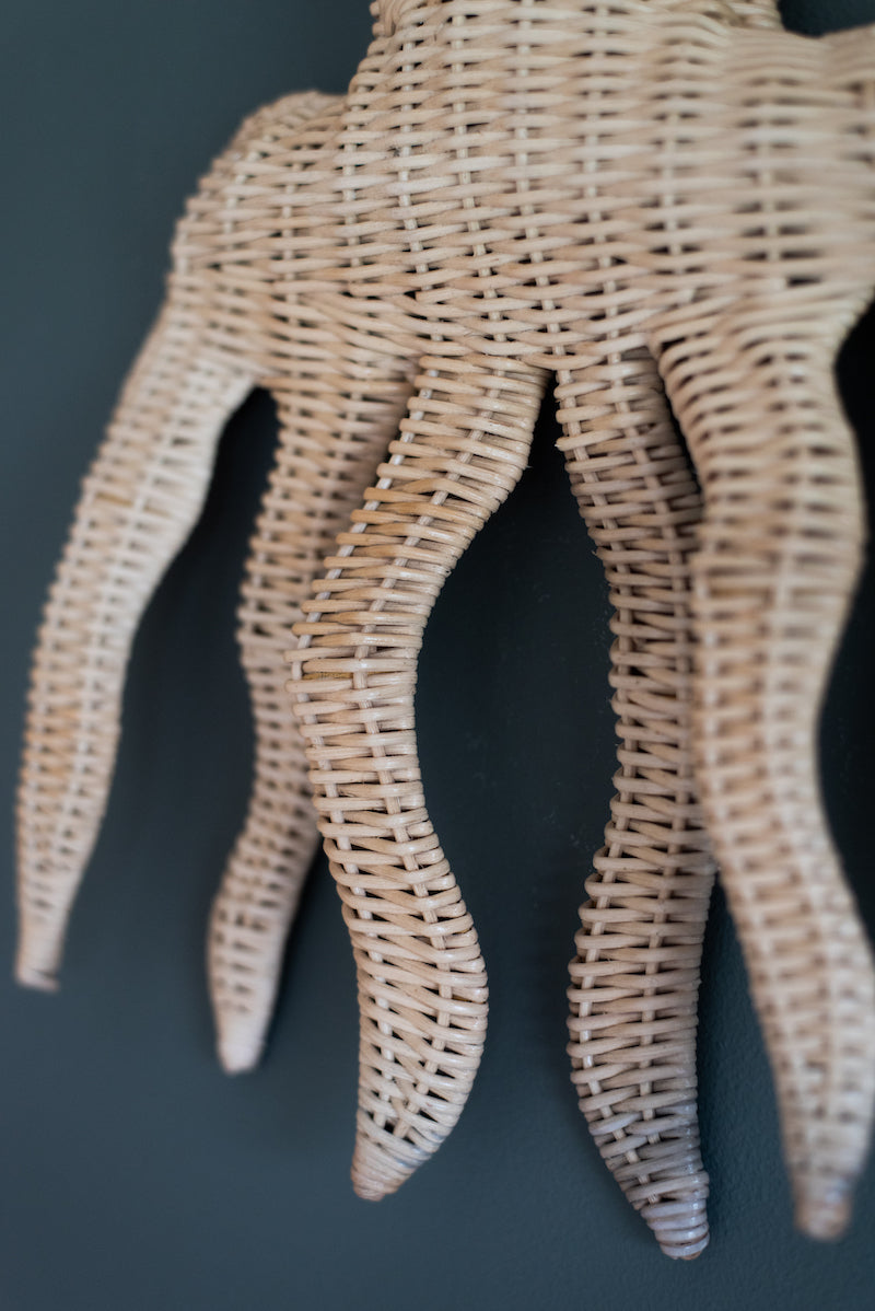 Op de afbeelding is een close-up te zien van een prachtige rotan octopus wanddecoratie, handgemaakt van duurzaam materiaal. Deze close-up foto toont de natuurlijke textuur en warme kleur van het rotan, en de aandacht voor detail en vakmanschap die is besteed aan de productie van dit mooie decoratieve stuk. Deze rotan octopus wanddecoratie voegt een speelse en organische uitstraling toe aan elke muur en is een stijlvolle en betekenisvolle aanvulling op elke ruimte..